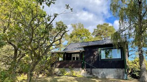 A small house with a dark exterior, a single visible window, and a sloped roof. - 4 Star Holiday Home in Rockneby (Rockneby)