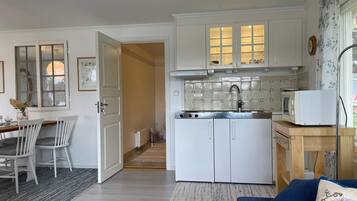 A compact living space with a kitchenette, a dining area with a table and chairs, and a sofa.