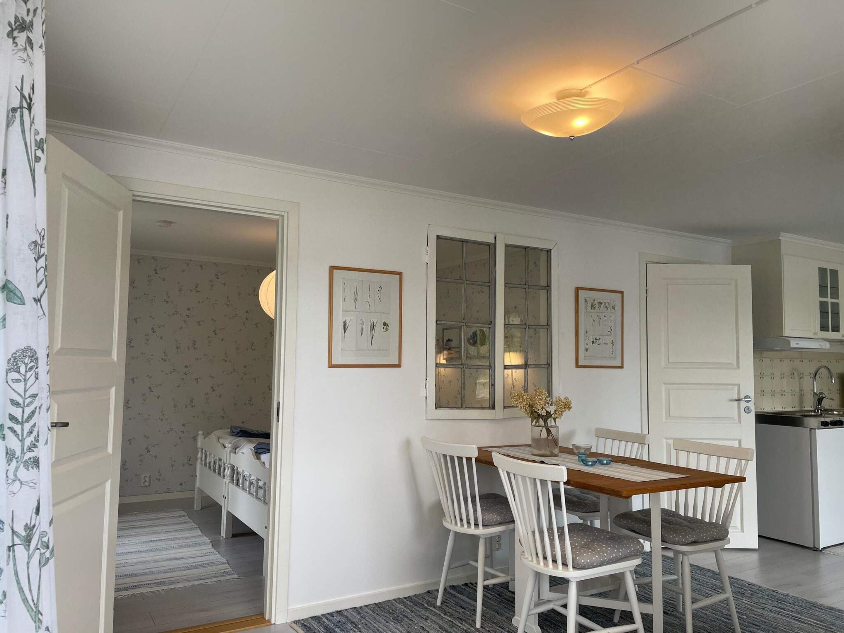 Una habitación con cama, una mesa de comedor con sillas, una zona de cocina y un ventanal con vidrio esmerilado.