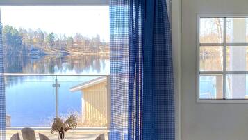 A room with a window overlooking a body of water and a building across the water.