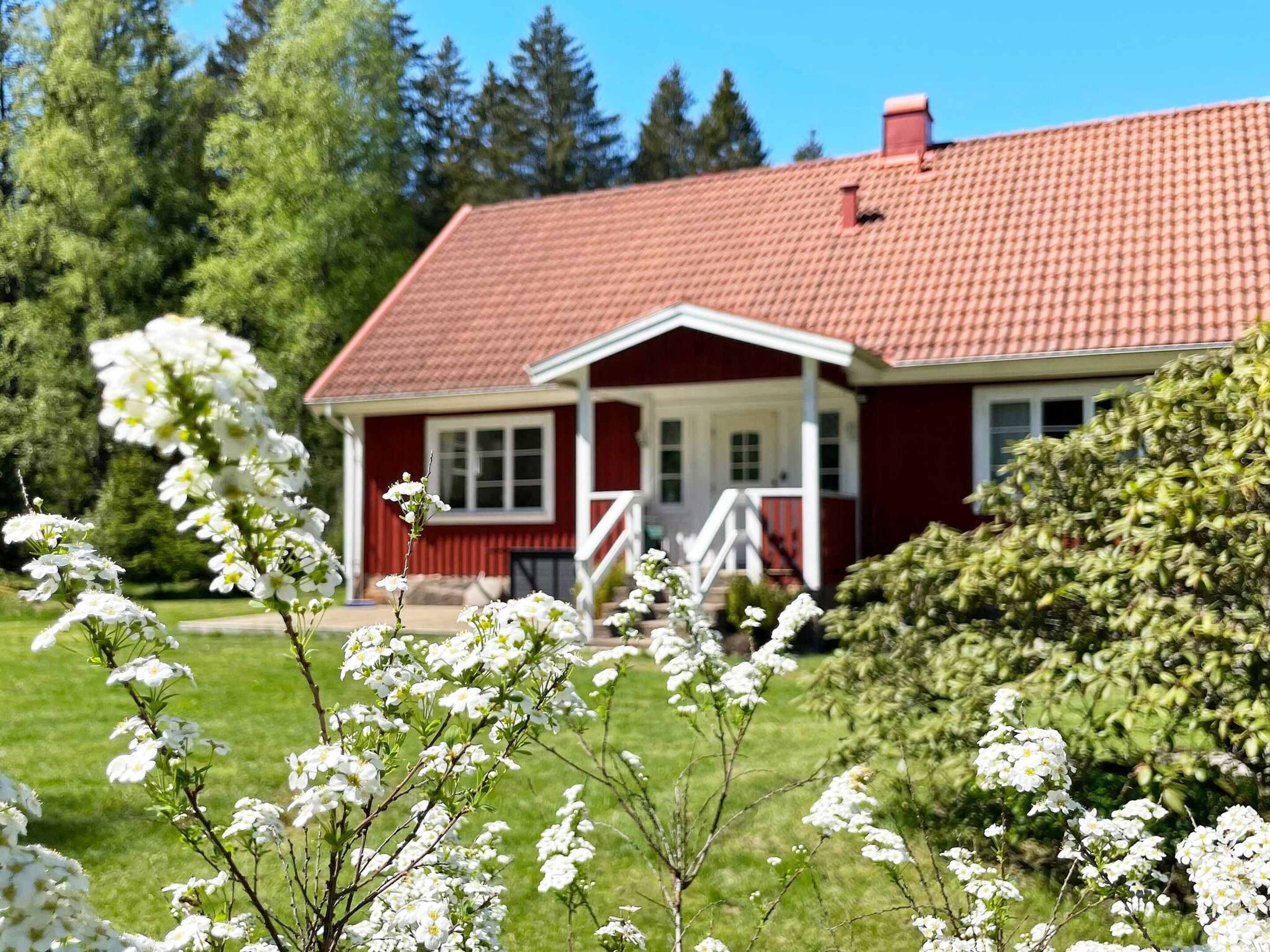 Une maison rouge avec un porche blanc et un toit rouge.