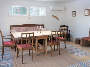 Ein Esszimmer mit Holztisch und -stühlen, einer gestreiften Bank und einem Fenster mit Blick auf Bäume.