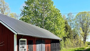 A red barn with a metal roof, a white door, and a window. - 4 Star Holiday Home in Hallabro (Hallaröd)
