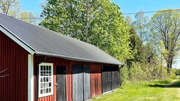 A red barn with a metal roof, a white door, and a window.
