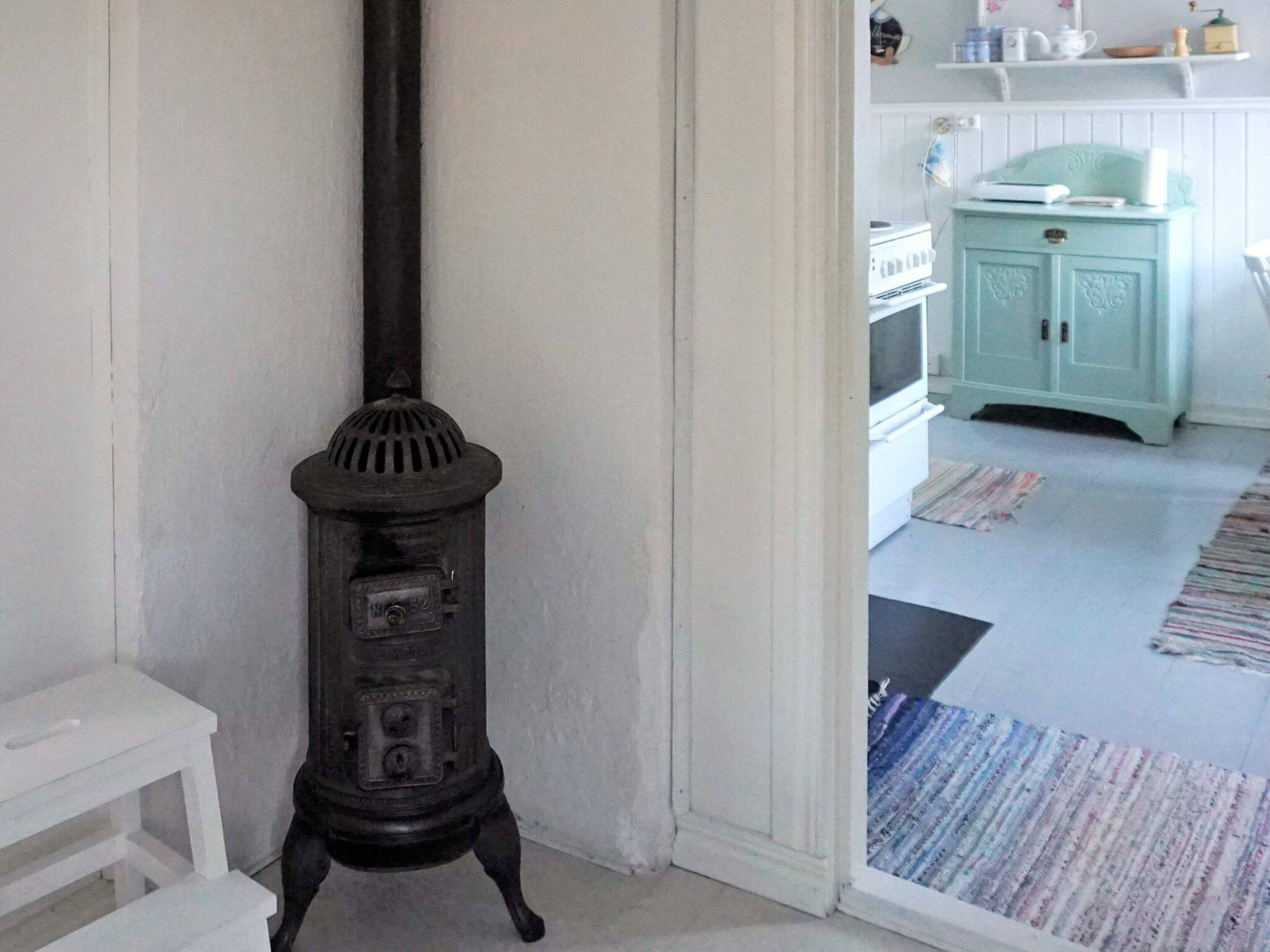 Ein Zimmer mit einem schwarzen Herd, weißen Wänden und einem türkisblauen Schrank.