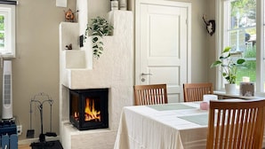 A cozy room with a fireplace, wooden chairs, a dining table, and a view of the outdoors.
