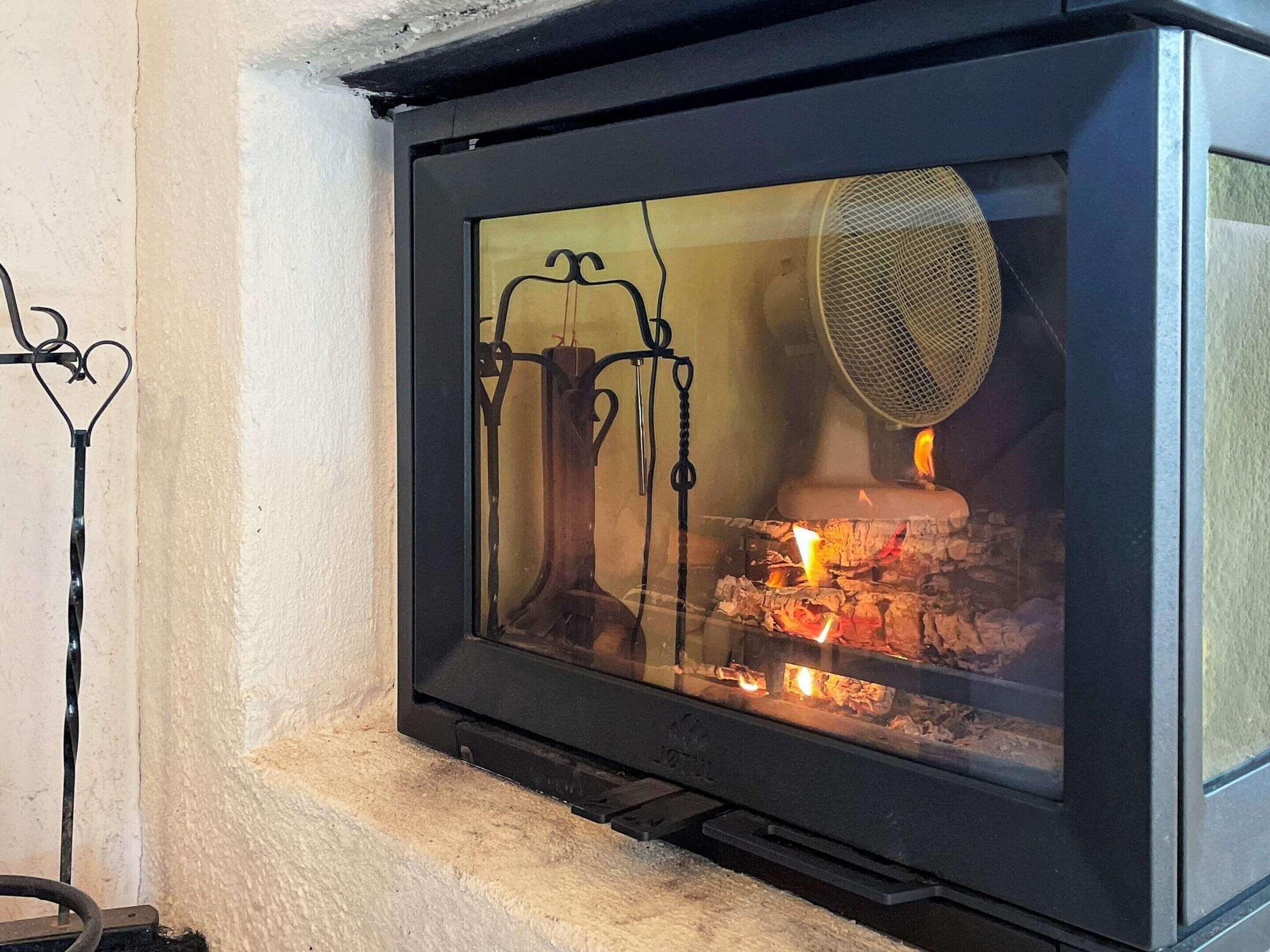 A fireplace with a glass screen and a fan above the fire.
