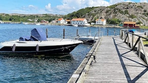 A wooden dock extending into calm water with a boat moored at the end.