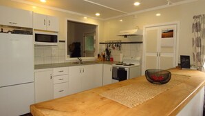 A modern kitchen with white cabinets, a wooden countertop, and a built-in oven. - Hibiscus Hideaway (Karikari Peninsula)