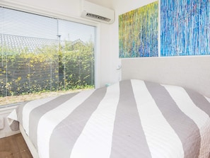 A bedroom with a bed, a window with blinds, and a wall with a painting. - 4 Person Holiday Home in Aabenraa (Aabenraa)