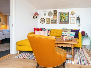 A cozy living room with a mustard yellow sofa, a wooden coffee table, and a colorful striped rug. - 4 Person Holiday Home in Aabenraa (Aabenraa)