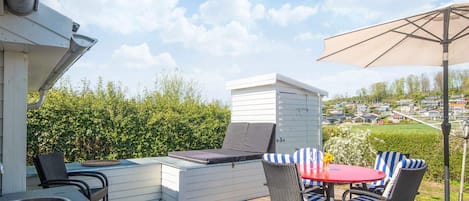 Una terraza con mesa y sillas, una parrilla y vistas a una zona residencial.