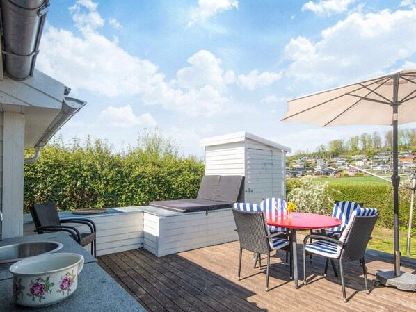 A deck with a table and chairs, a grill, and a view of a residential area. - 4 Person Holiday Home in Aabenraa (Aabenraa)