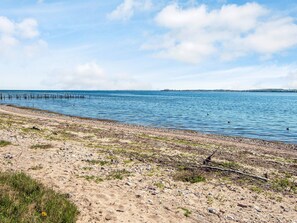 A beach with a sandy shore and a wooden pier extending into calm waters. - 4 Person Holiday Home in Aabenraa (Aabenraa)