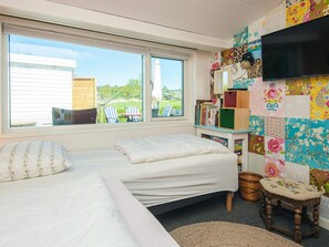 Ein Schlafzimmer mit Bett, Fernseher, Bücherregal und Fenster mit Blick nach draußen.