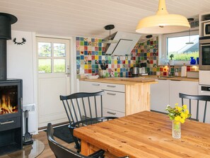 Eine moderne Küche mit Kaminofen, farbenfrohen Fliesen und einem Essbereich mit Holztisch und Stühlen.
