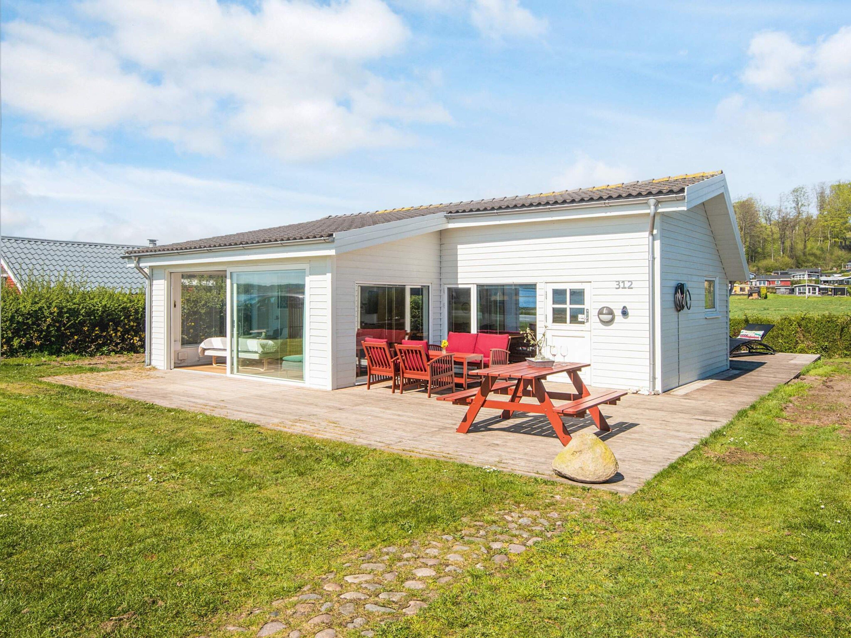 Une maison moderne dotée d’un patio, d’un coin repas et d’un espace extérieur aménagé et abrité.