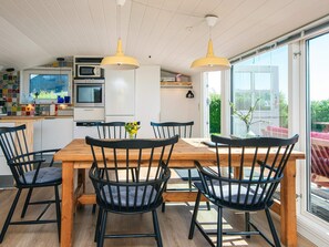 A modern kitchen with white cabinets, a wooden dining table, and black chairs. - 4 Person Holiday Home in Aabenraa (Aabenraa)