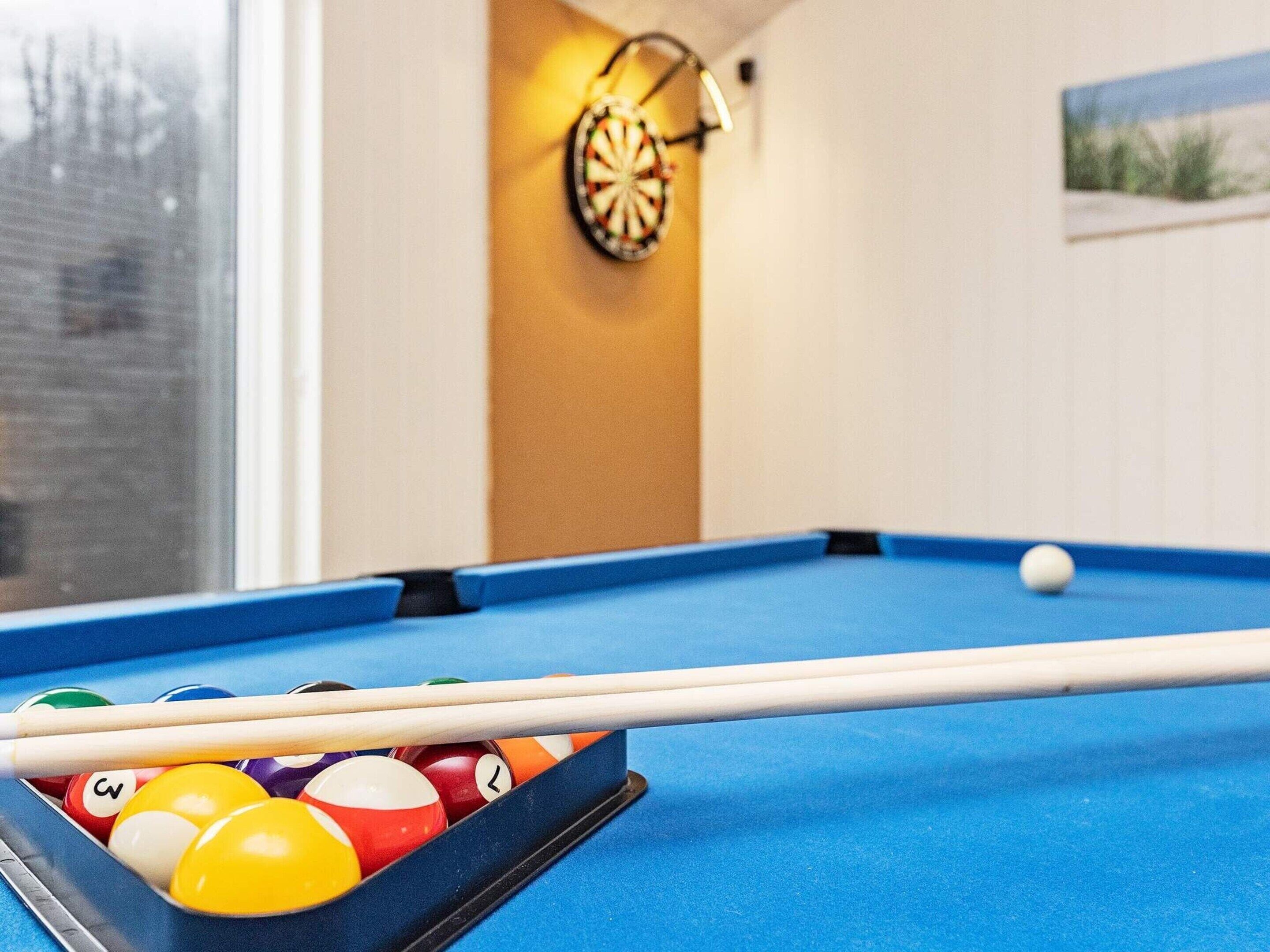A pool table with balls and a cue stick.