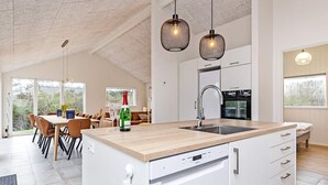 Una cocina moderna con una isla central, armarios blancos e iluminación colgante.