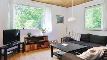 Uma sala de estar acolhedora com televisão, estantes, sofá e mesa de jantar.