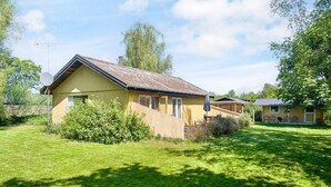 Ein eingeschossiges Holzhaus mit geneigtem Dach, einer Satellitenschüssel und einer kleinen Terrasse mit Tisch und Stühlen.