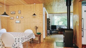 A wooden interior with a dining table, chairs, a television, and a wood stove. - 6 Person Holiday Home in Hojby (Hojby)