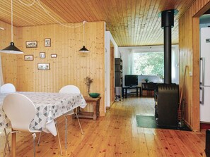 A wooden interior with a dining table, chairs, a television, and a wood stove. - 6 Person Holiday Home in Hojby (Hojby)
