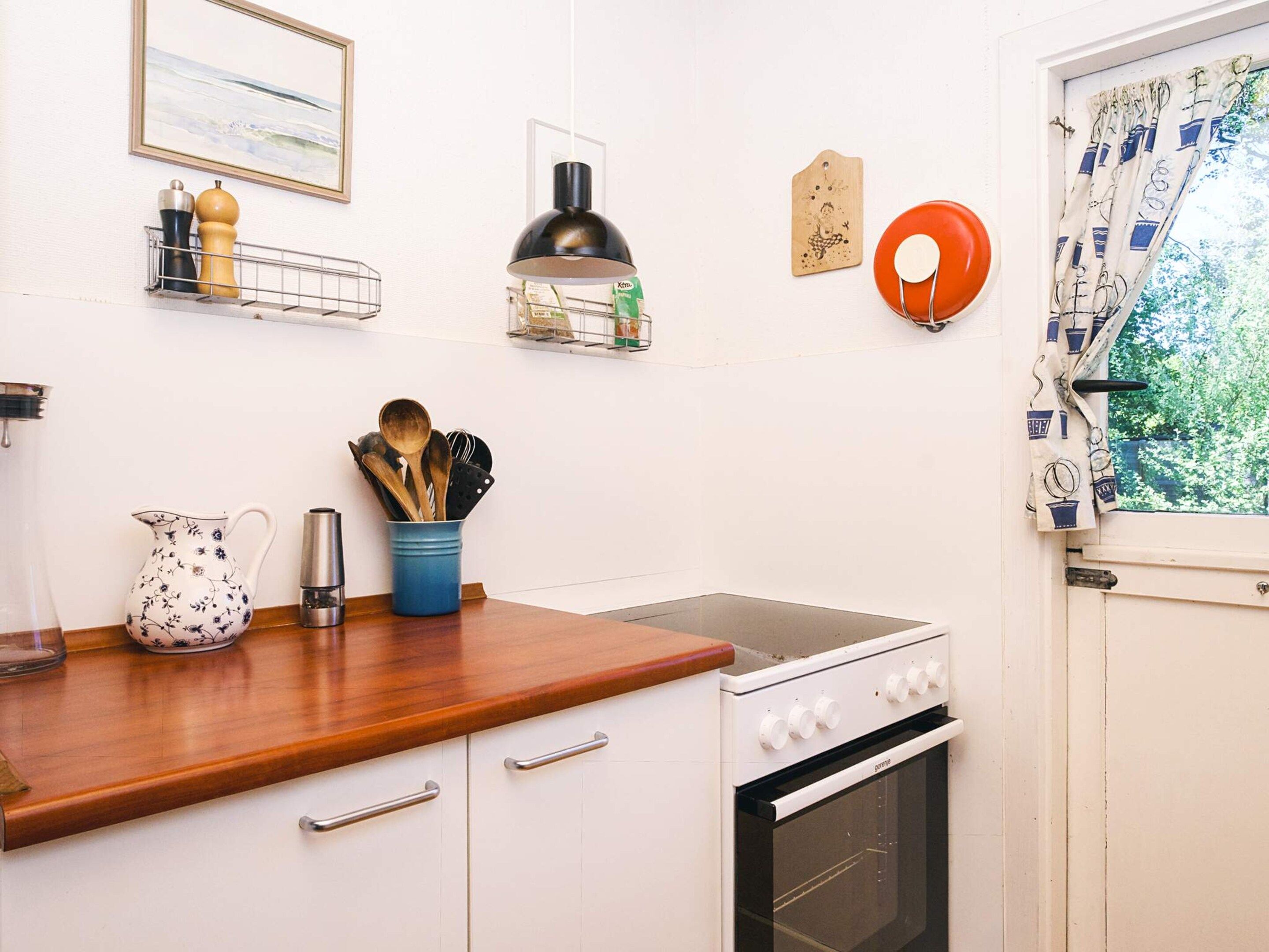 Una cocina con estufa, horno, encimera de madera y diversos utensilios de cocina.
