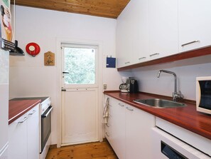A compact kitchen with white cabinets, a wooden countertop, a stainless steel sink, and a coffee maker. - 6 Person Holiday Home in Hojby (Hojby)