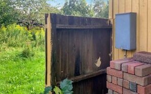 A wooden gate, a brick wall, and a blue electrical box. - 6 Person Holiday Home in Hojby (Hojby)