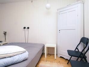 A bedroom with a bed, a chair, a desk, and a door. - 6 Person Holiday Home in Hojby (Hojby)
