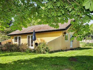A single-story wooden house with a sloped roof, a front porch, and a small garden area. - 6 Person Holiday Home in Hojby (Hojby)