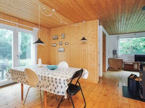 Un intérieur en bois comprenant une table à manger, des chaises, un luminaire suspendu et des tableaux encadrés accrochés au mur.