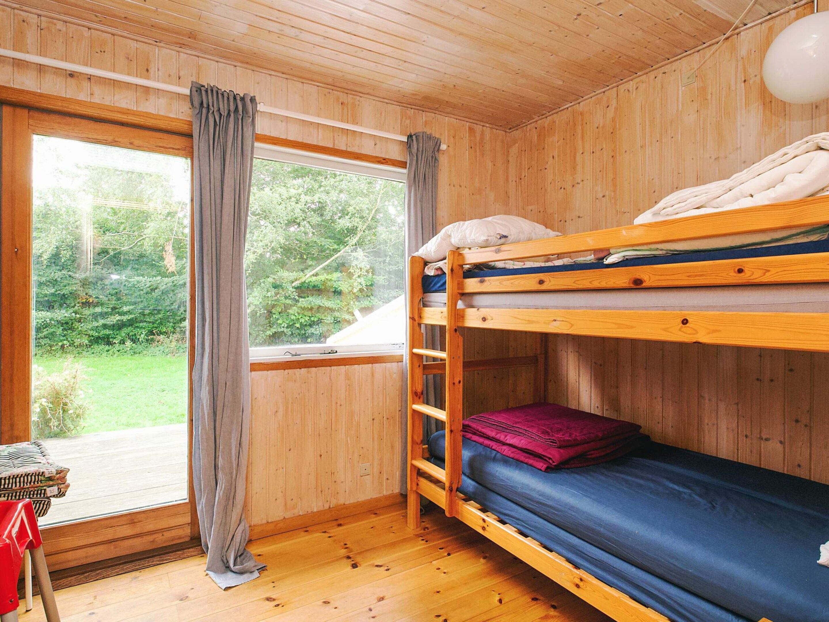 Habitación con literas, paredes de madera y vistas al exterior.