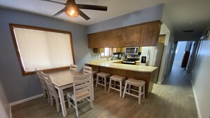 A modern kitchen with a central island, wooden cabinets, and a dining area with a table and chairs. - SilverKing Family Retreat - Dog Friendly! (Show Low)