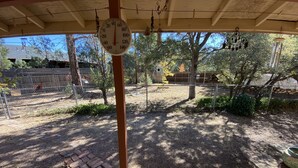 A covered outdoor area with a wooden bench, a hanging thermometer, and a fenced garden. - SilverKing Family Retreat - Dog Friendly! (Show Low)