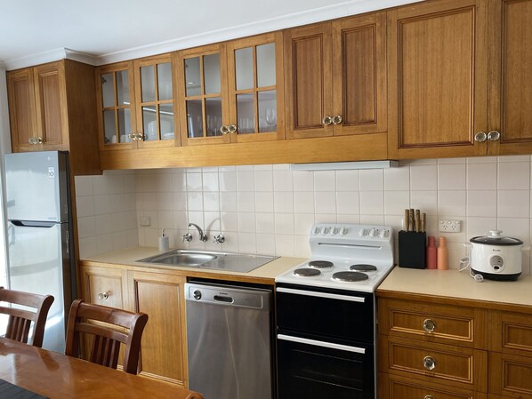 A kitchen with wooden cabinets, a stainless steel refrigerator, a dishwasher, a stove, and a coffee maker. - Immaculate Apartment in Lenah Valley, 4.5 KM’s to the Hobart CBD (Lenah Valley)