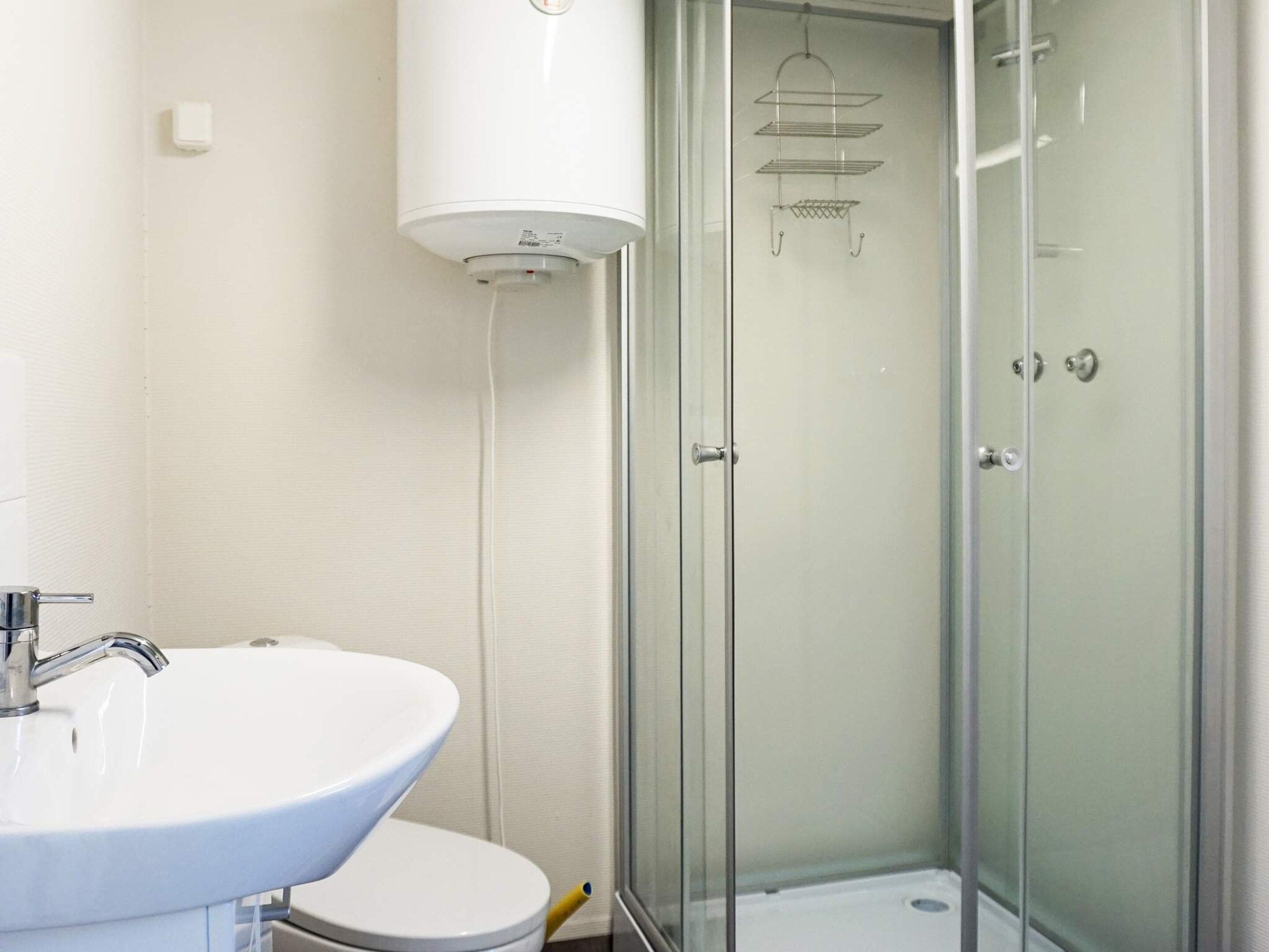 A bathroom with a white sink, toilet, and a glass-enclosed shower area.