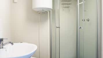 A bathroom with a white sink, toilet, and a glass-enclosed shower area.