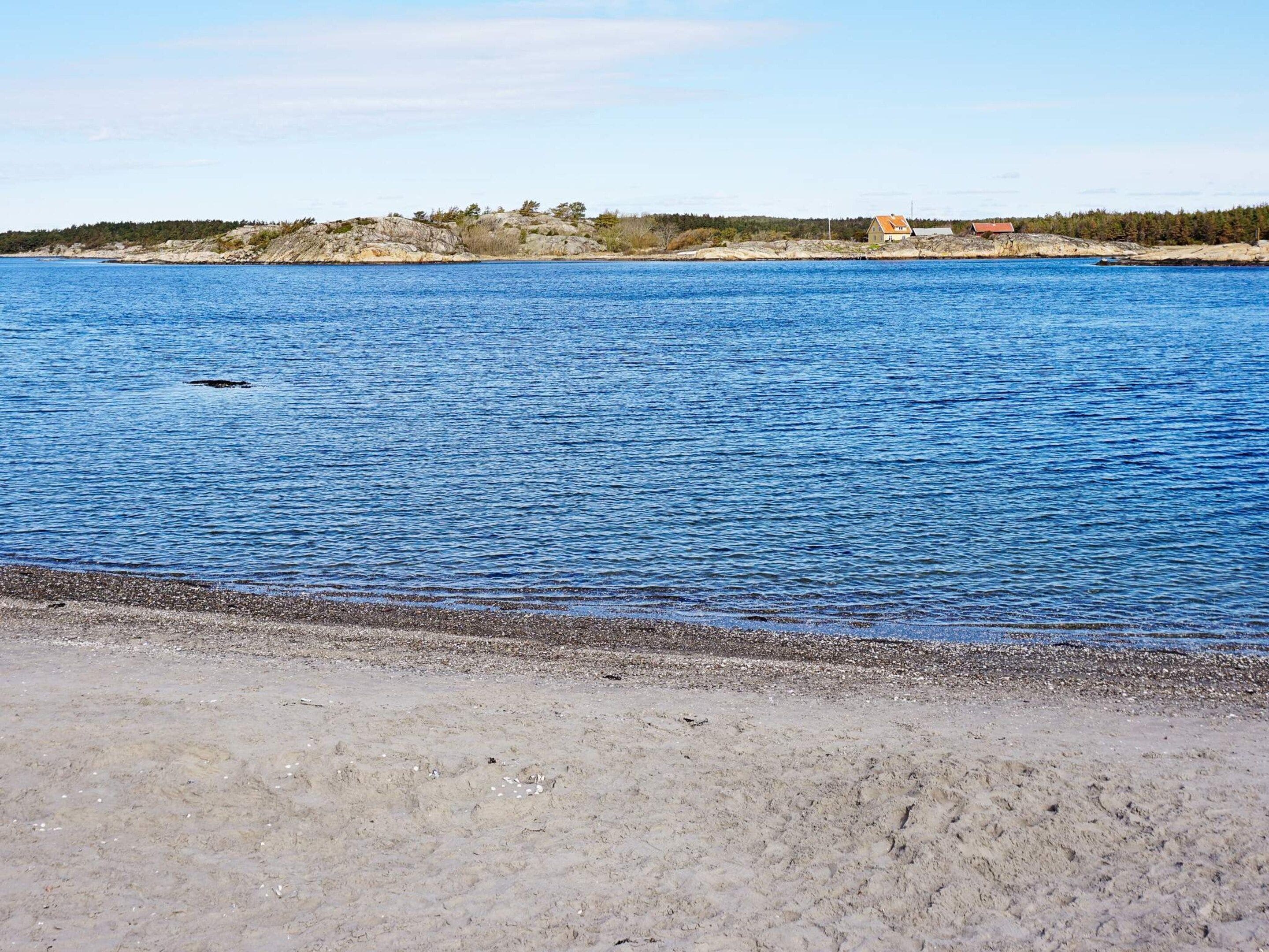 A coastal landscape with a clear view of the sea, a rocky shoreline, and a distant building.