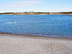 Eine Küstenlandschaft mit freiem Blick auf das Meer, einer felsigen Küstenlinie und einem Gebäude in der Ferne.