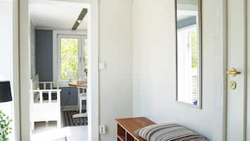 A hallway with a wooden bench, a mirror, and a door leading to a room with a window.