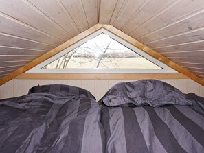 Ein kleines Schlafzimmer im Dachgeschoss mit schrägen Wänden und einem dreieckigen Fenster.