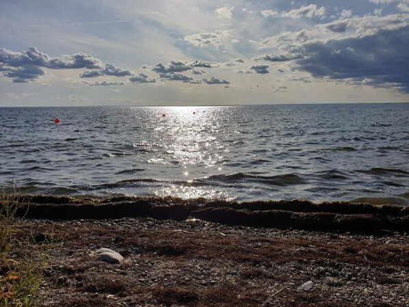 Un paisaje costero con una costa rocosa, mar tranquilo y cielo parcialmente nublado.