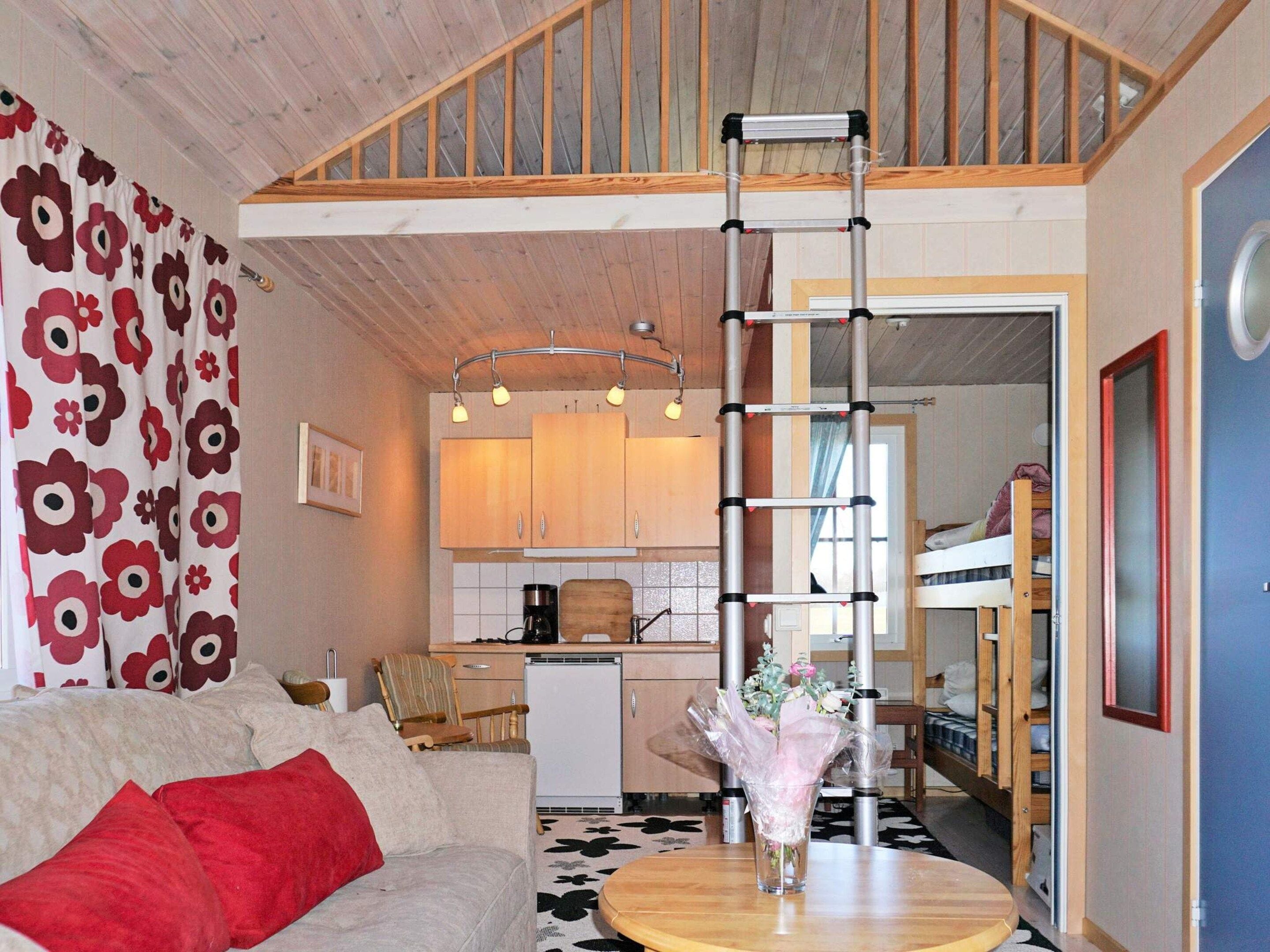 A compact living space with a kitchenette, a dining area, and a loft bedroom with a ladder.