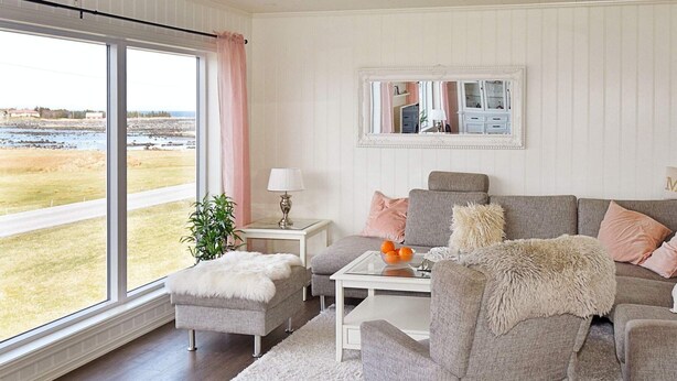 A living room with a large window, a grey sofa, a white coffee table, and a fluffy ottoman. - 8 Person Holiday Home in Leinoy-by Traum (Heroy)