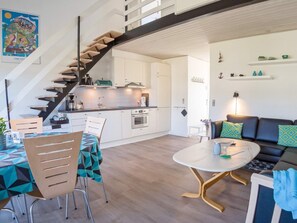 A modern kitchen with white cabinets, a wooden staircase, and a dining area with a table and chairs. - 6 Person Holiday Home in Vestervig (Vestervig)