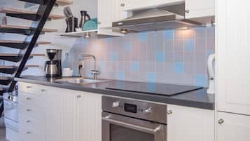 Una cocina moderna con campana de acero inoxidable, horno empotrado y cafetera sobre la encimera.