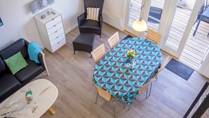 Espaço compacto com mesa de jantar, sofá, uma cadeira, televisão e pequena cozinha.